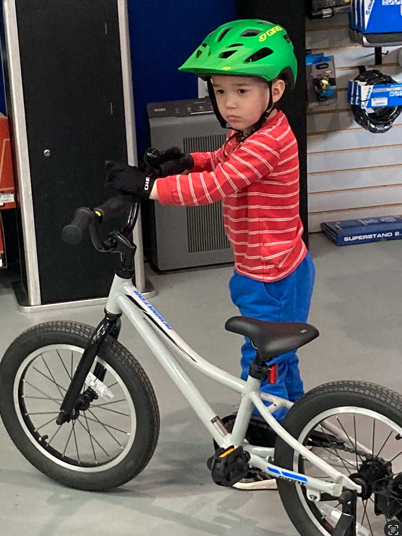 Boy wearing helmet and walking bike he won from Southeast Greenway