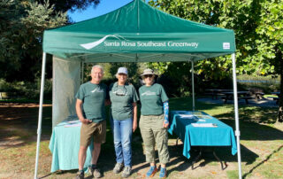 3 men standing in front of the green Southeast Greenway tent