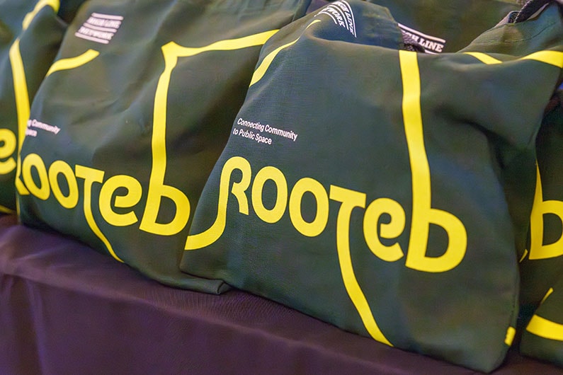 Close up photo of green conference bags with the "Rooted" logo