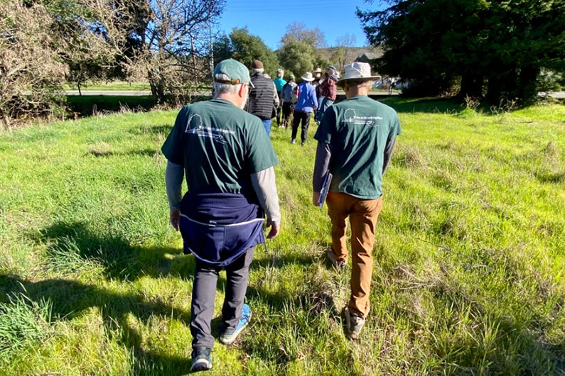 Two greenway volunteers wearing green t-shirts guiding a group on a walk