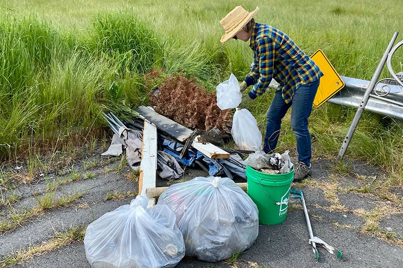 Woman gathering trash at the Southeast Greenway clean up day