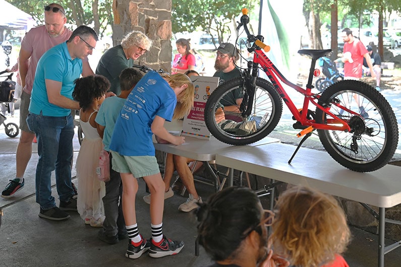 Kids entering contest for free bike at Child in the Wild. Red bike displayed on table