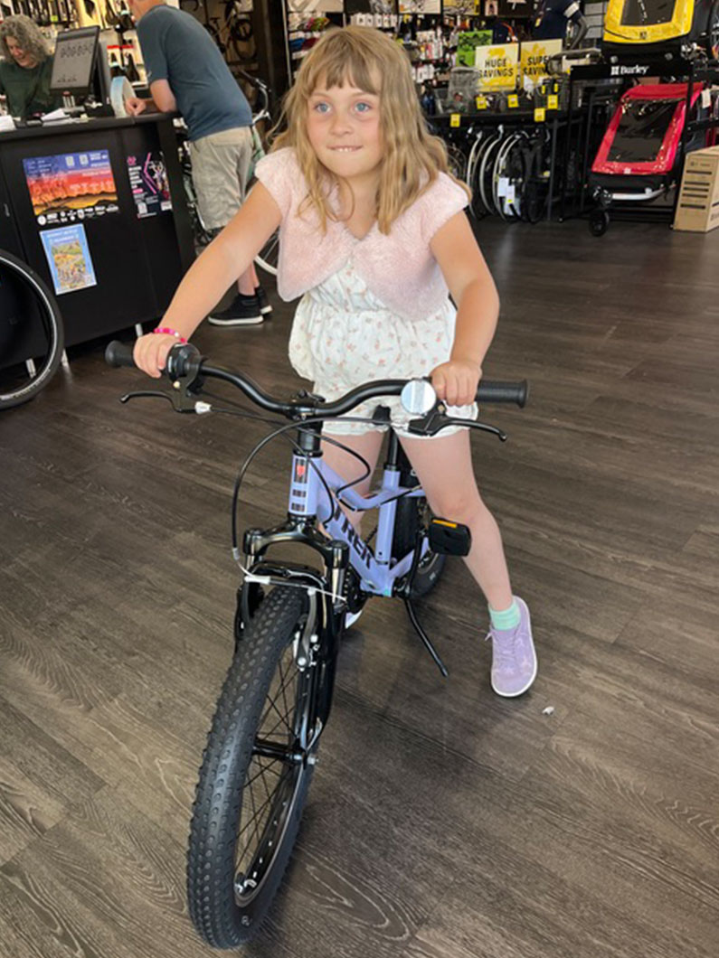 Girl sitting on bicycle that she won at a raffle at Child in the Wild