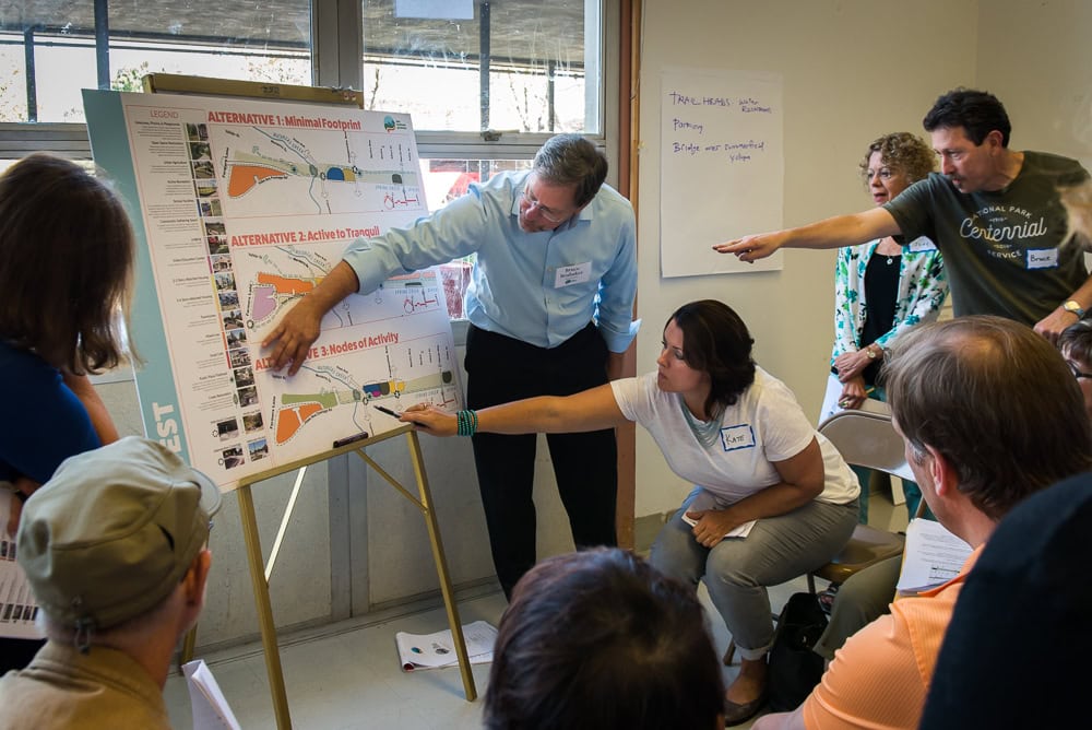 Community members gathered around an easel reviewing map design alternatives during a planning workshop.